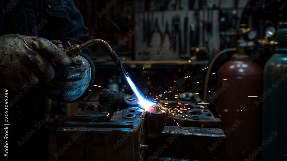 Brazing torch creating sparks on metal in a workshop